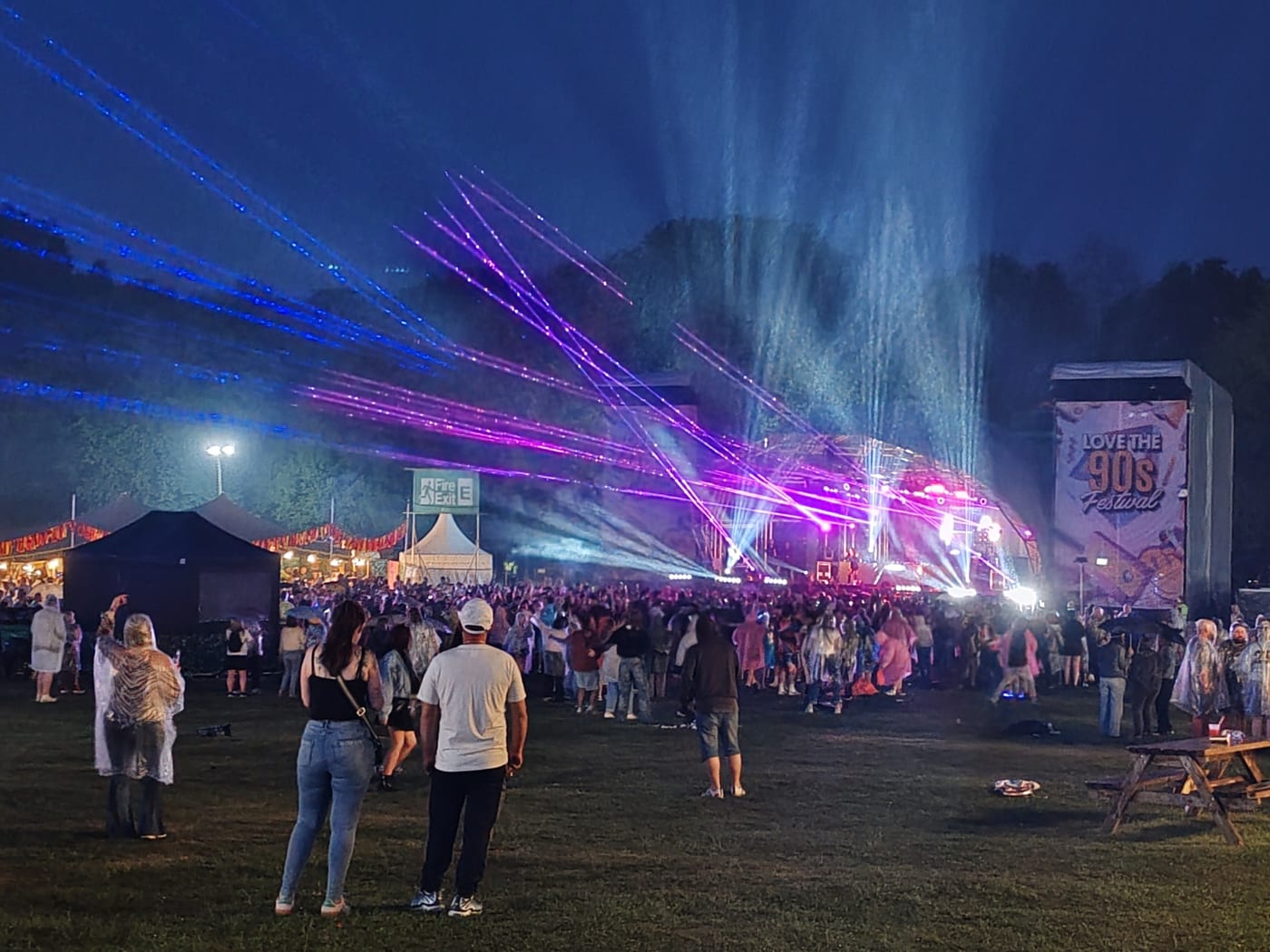 A night-time festival crowd beneath a laser show, kept safe by BelvoirCare's event medics.