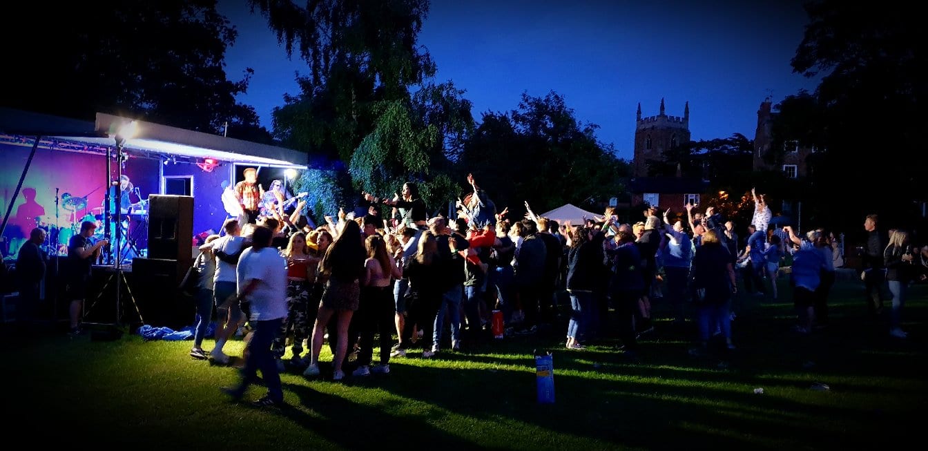 An evening open-air live music event on a village green, covered by BelvoirCare medics.