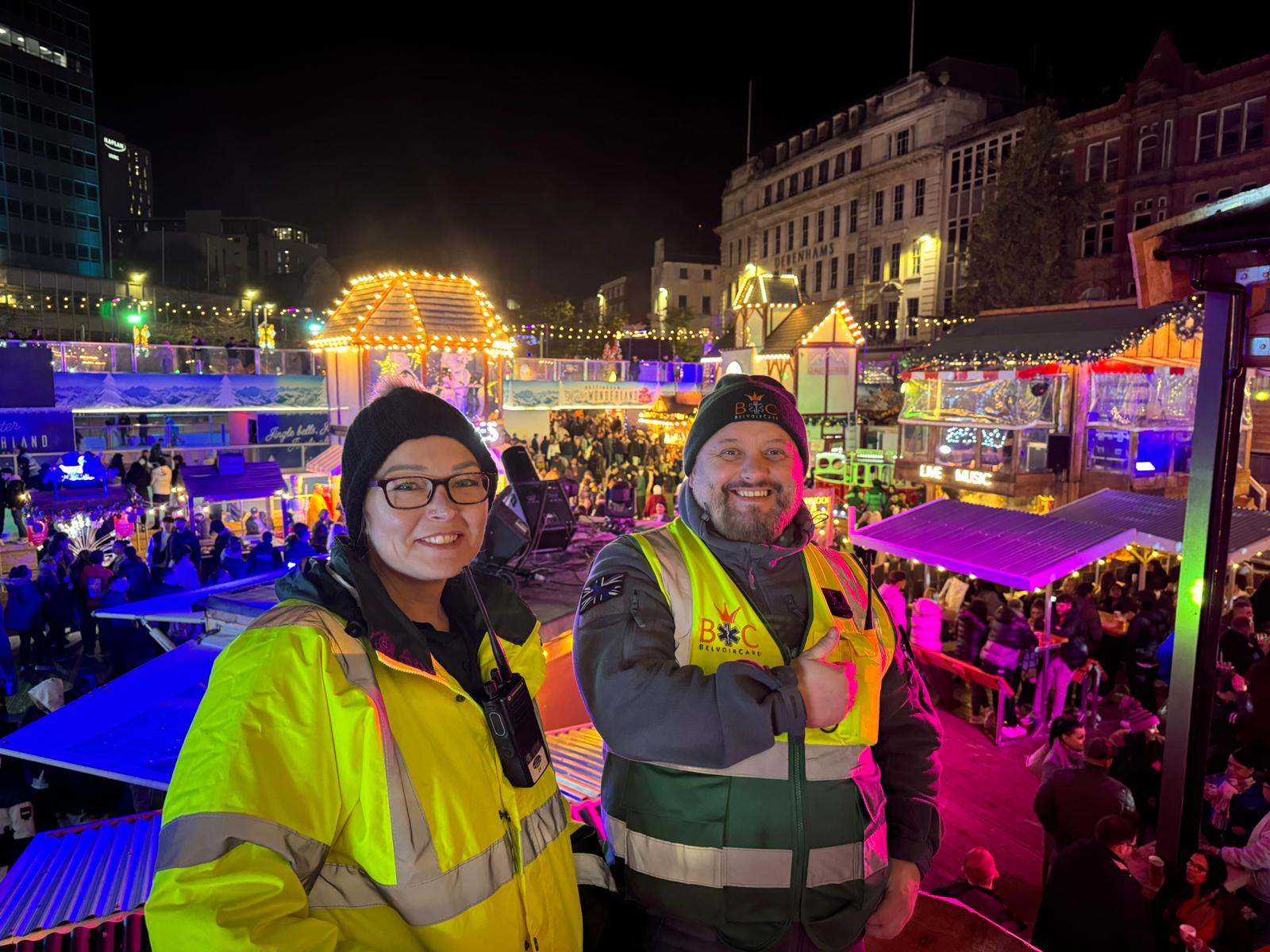 Two smiling BelvoirCare medics on duty at a busy winter city-centre event.